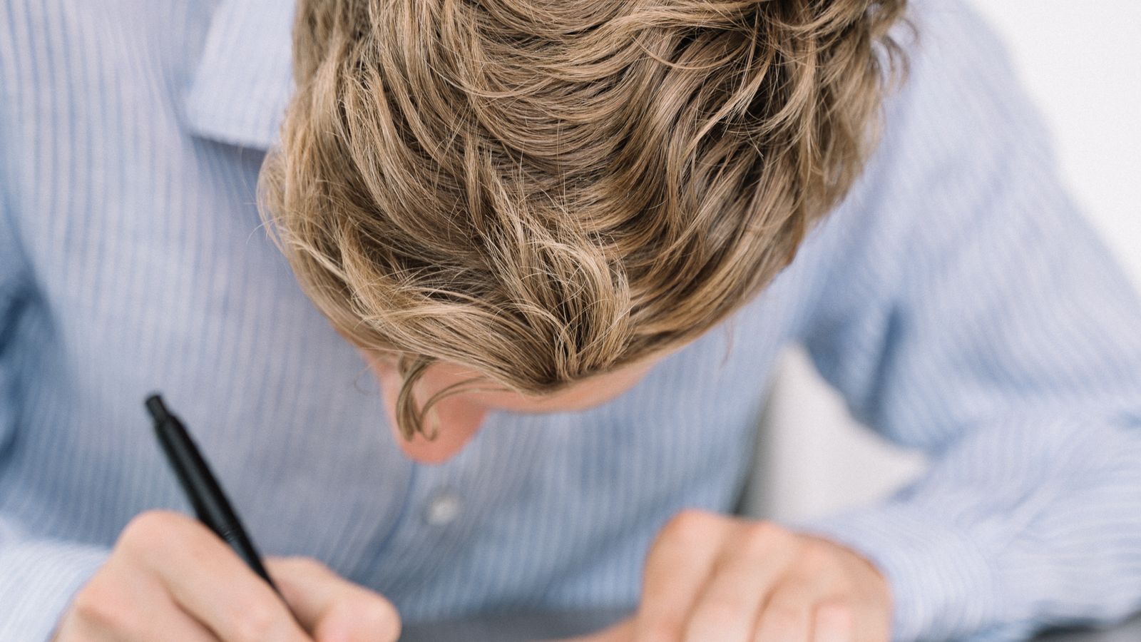Young man focused on handwriting notes in a notebook at a table