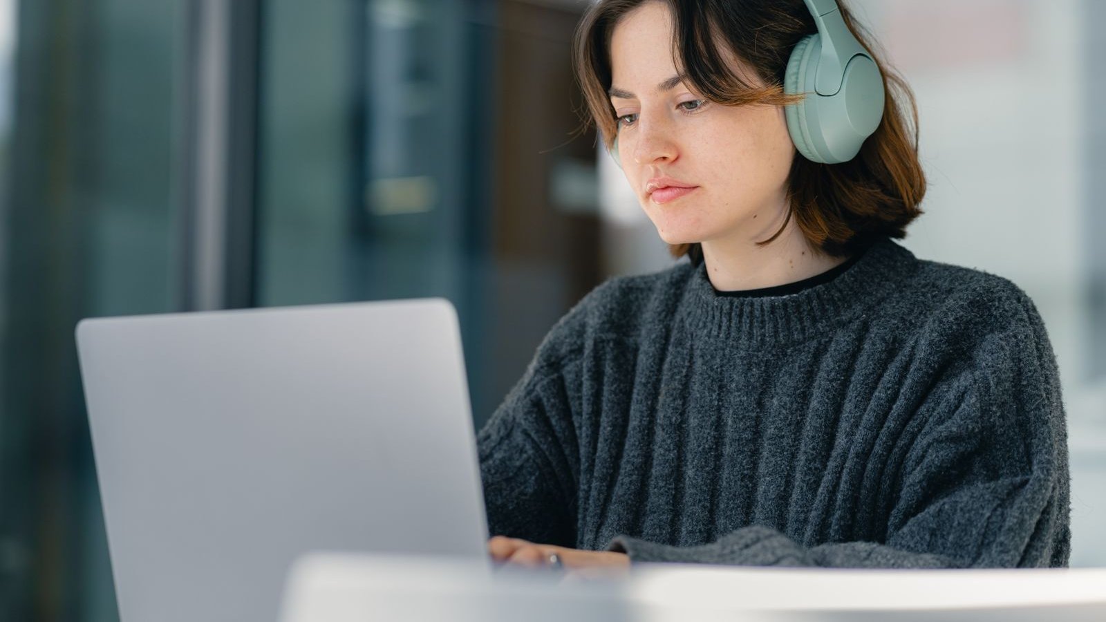 Focused woman wearing headphones while working on a laptop