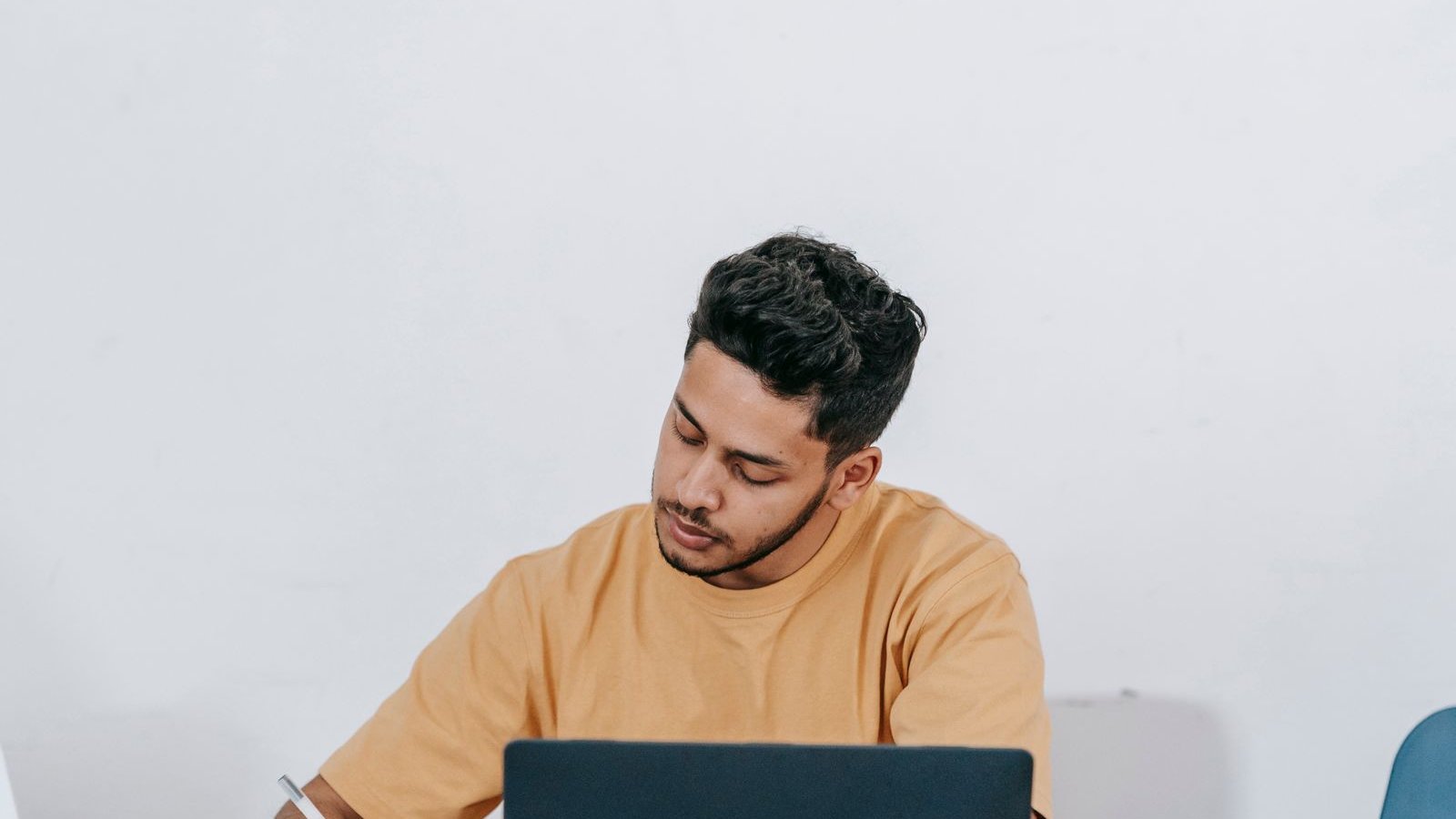 Remote worker taking notes beside a laptop at home