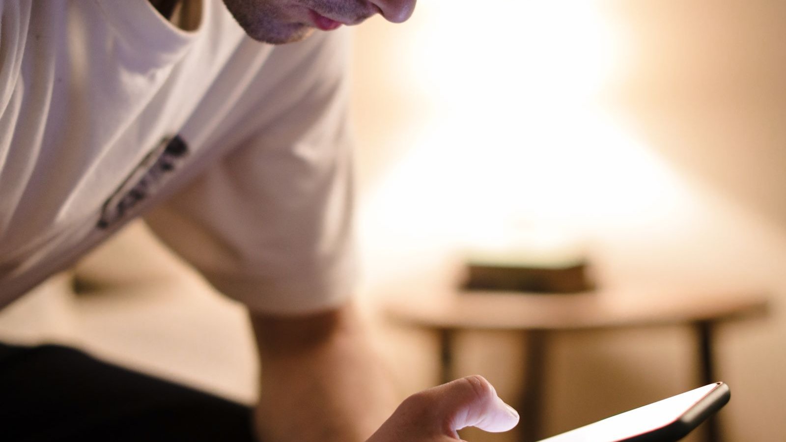 Young person sitting on their bed absorbed in their phone