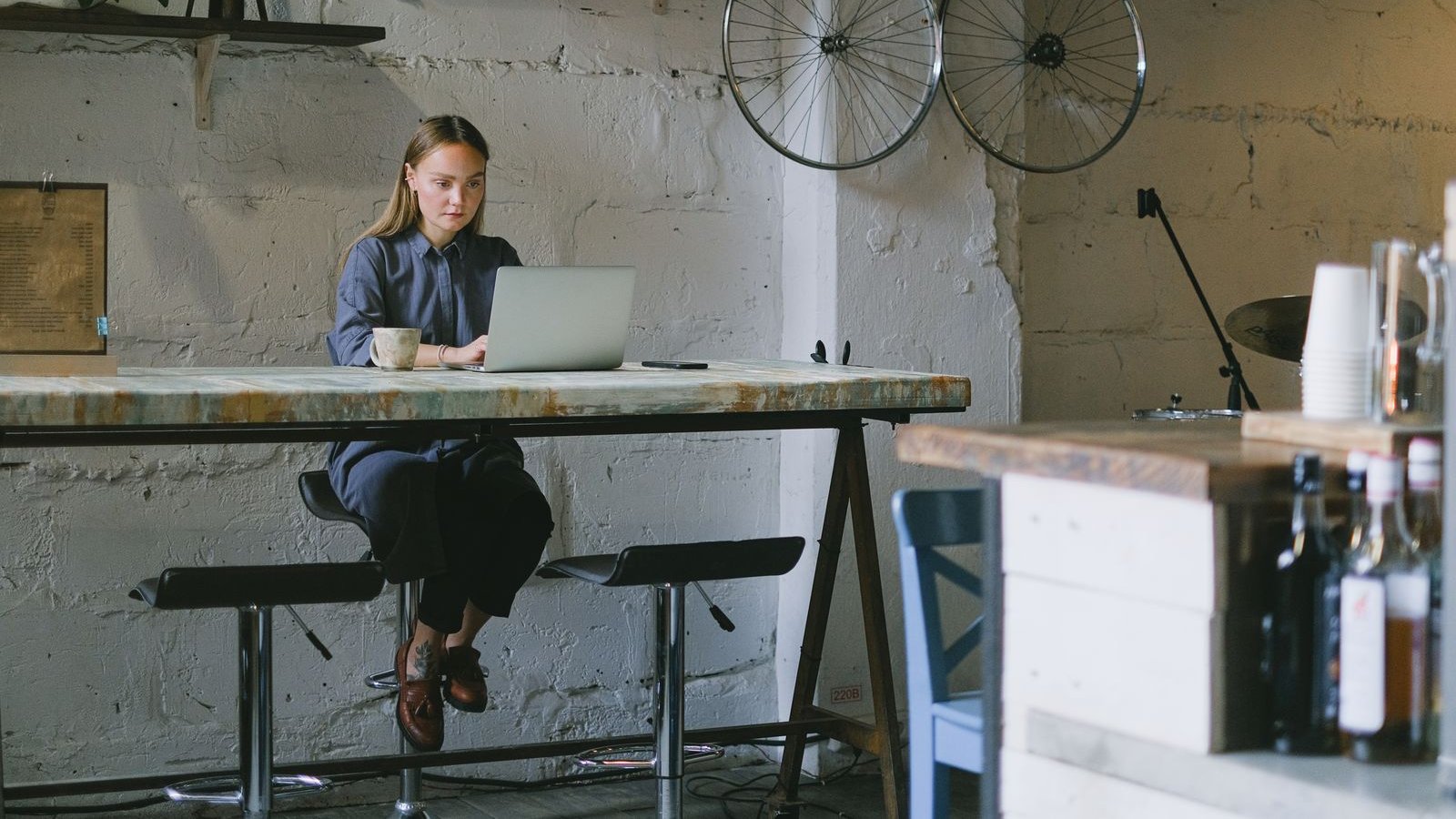 Woman working remotely on a laptop with a cup of coffee in a loft