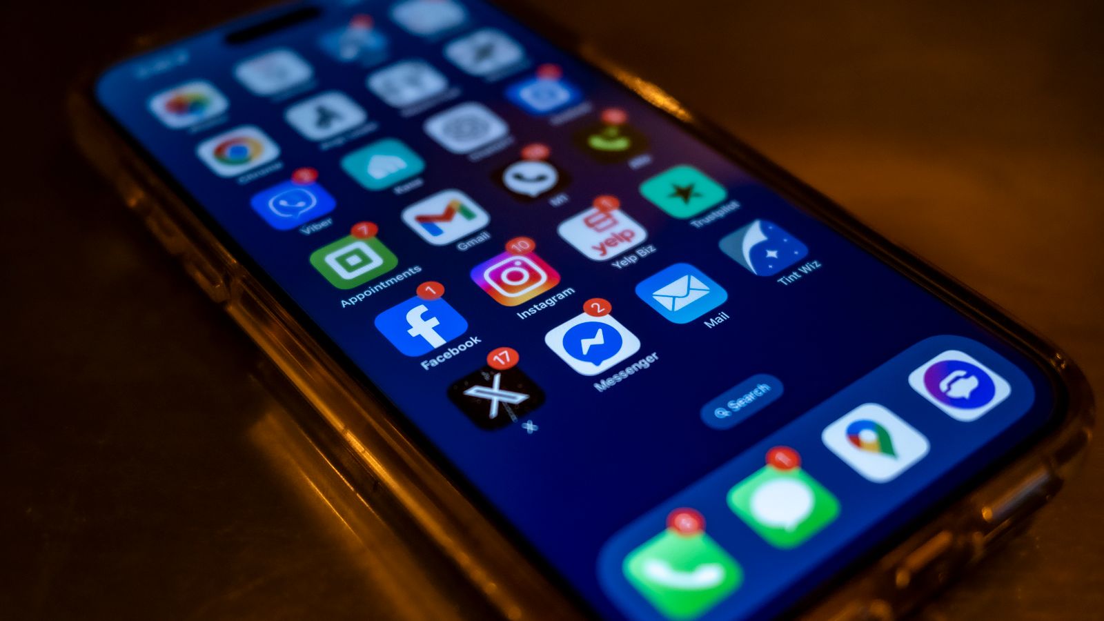 Smartphone screen displaying social media app notifications in a dimly lit setting