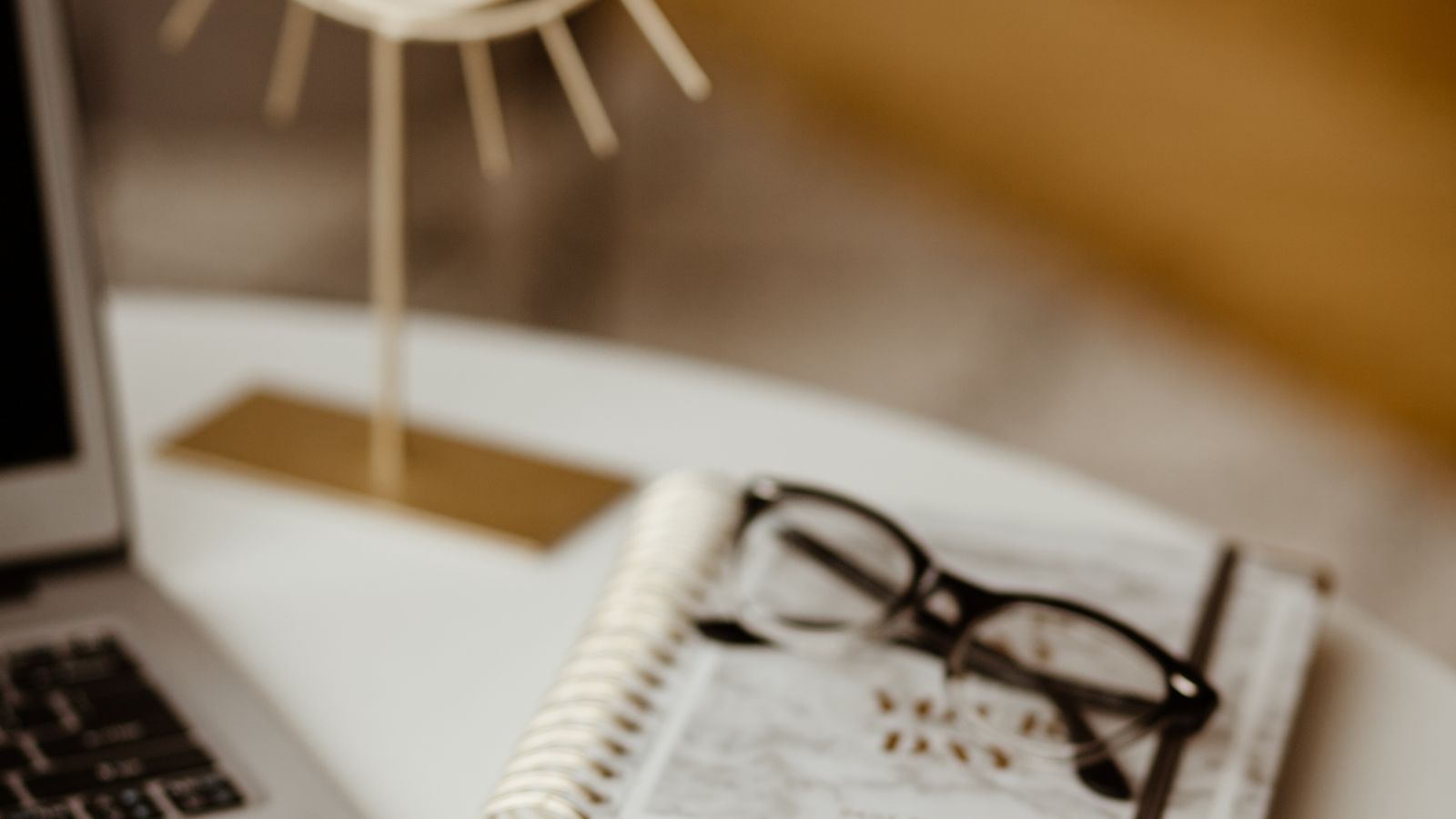 Stylish home office with a laptop, planner, glasses, and phone on a cozy desk