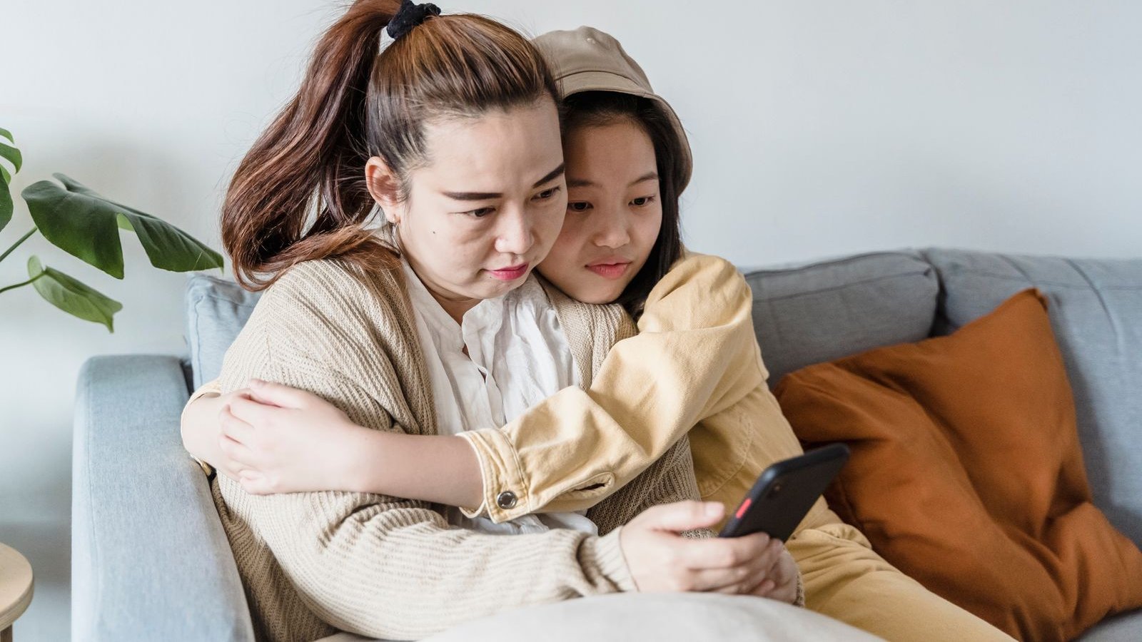 Mother and daughter looking at a smartphone together on a couch