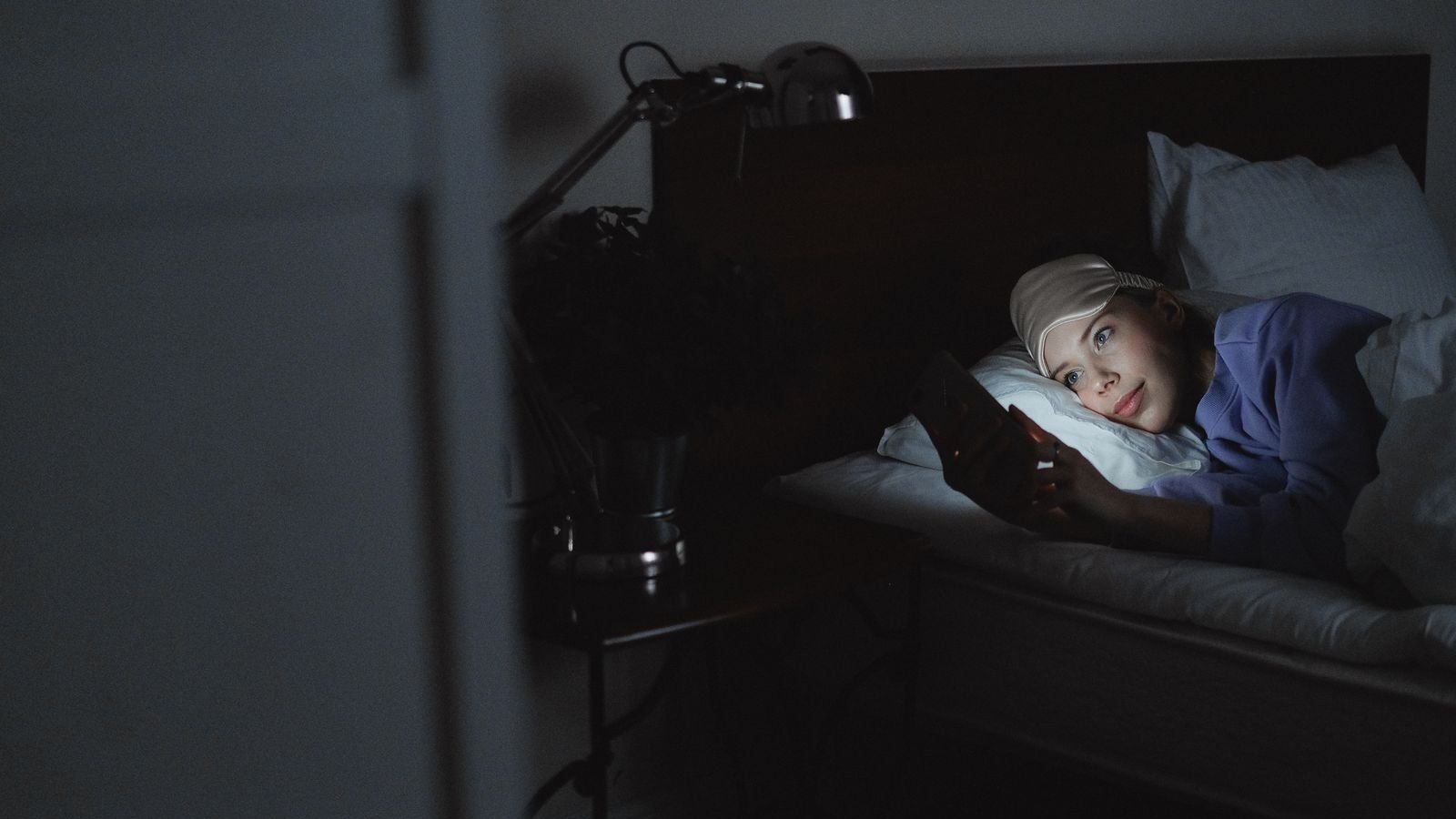 Woman lying in bed at night using a smartphone