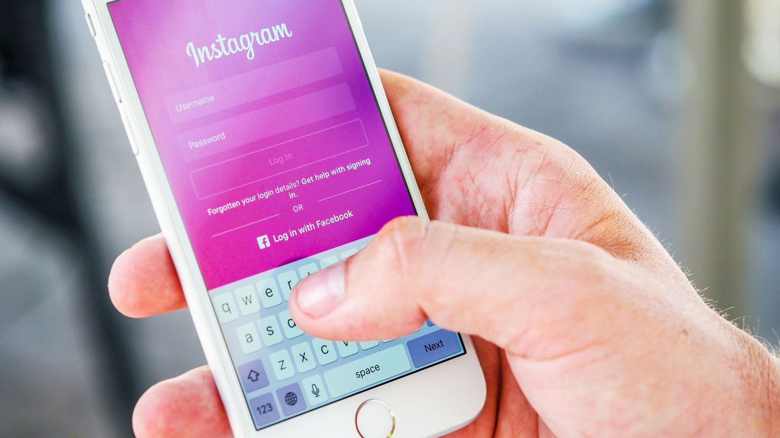 Close-up of a hand holding a phone open to the Instagram login screen