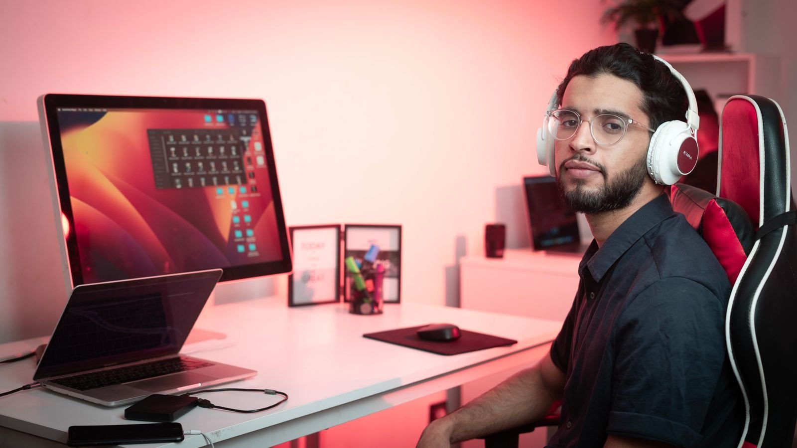 Man wearing headphones working at a desk with dual monitors