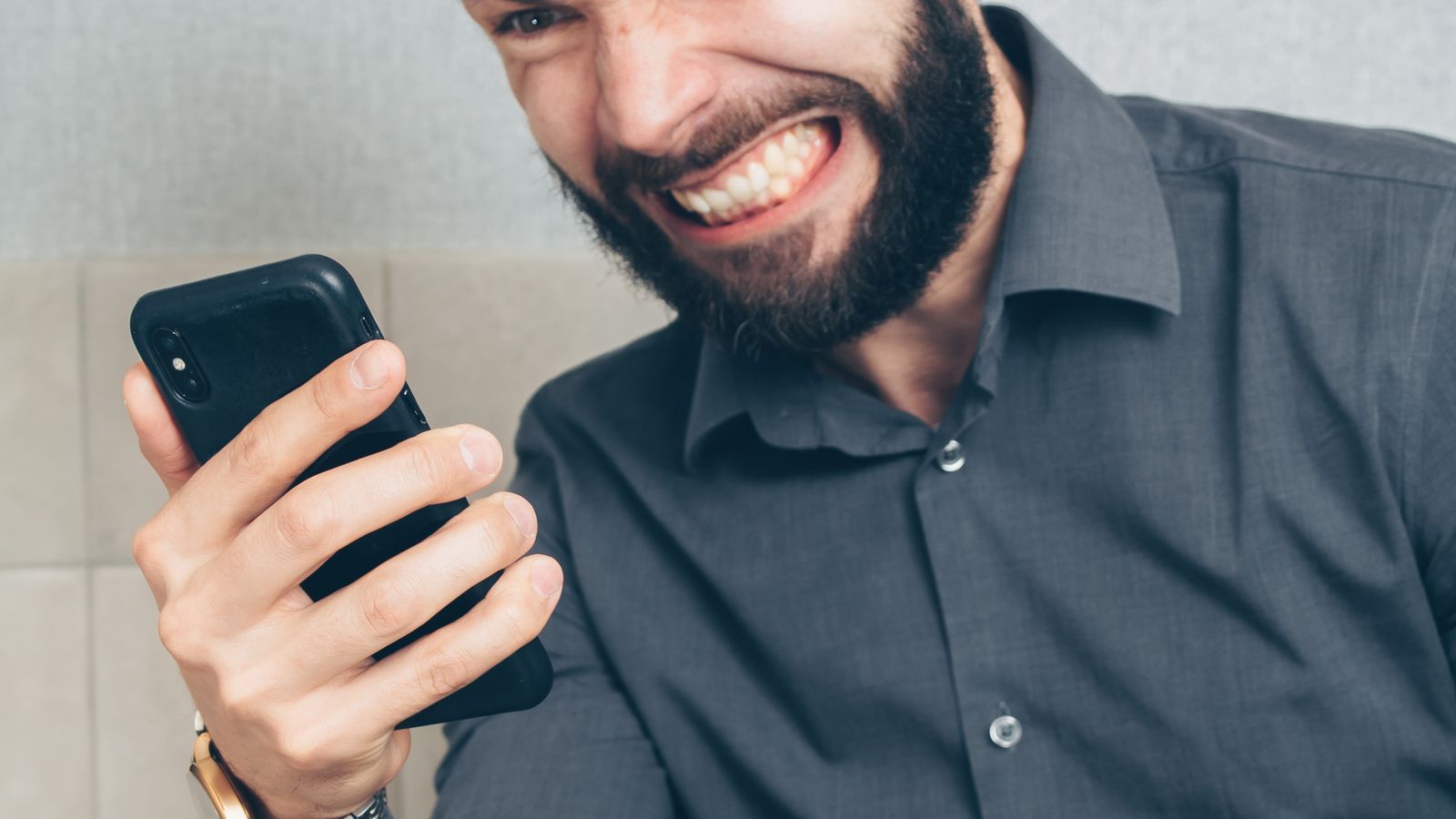 Man in an office looking frustrated while holding his smartphone